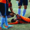 A group of soccer players standing around a man on the ground (Photo: Luis Quintero on Unsplash).